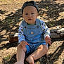 child, toddler, baby, overalls, cap, barefoot, grass, sunlight, shadow, outdoor, log, fence, curious, sitting, nature, clothing, face, person, summer, playful