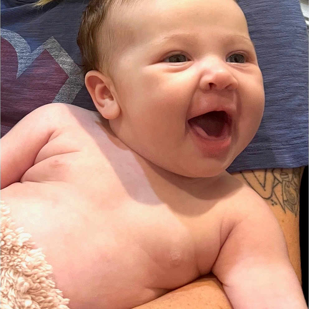 Roselee joined the competition — help win amazing prizes! baby, infant, child, smiling, laughing, portrait, close_up, indoor, being_held, parent, adult, face, eyes, open_mouth, bare_skin, blanket, braid, tattoo, purple_shirt, happy