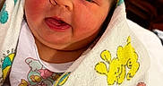 Roselee is registered to the contest to win money with this photo: newborn, baby, infant, child, face, portrait, eyes, mouth, smiling, blanket, swaddled, cartoon, colorful, indoors, close_up, person, arms, tattoo, crib, cozy