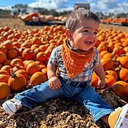 Nathaniel is registered to the contest to win money with this photo: toddler, child, pumpkins, orange, autumn, outdoor, smiling, happy, plaid_shirt, bandana, jeans, sneakers, sunny, daylight, nature, fall, ground, woodchips, portrait, seasonal