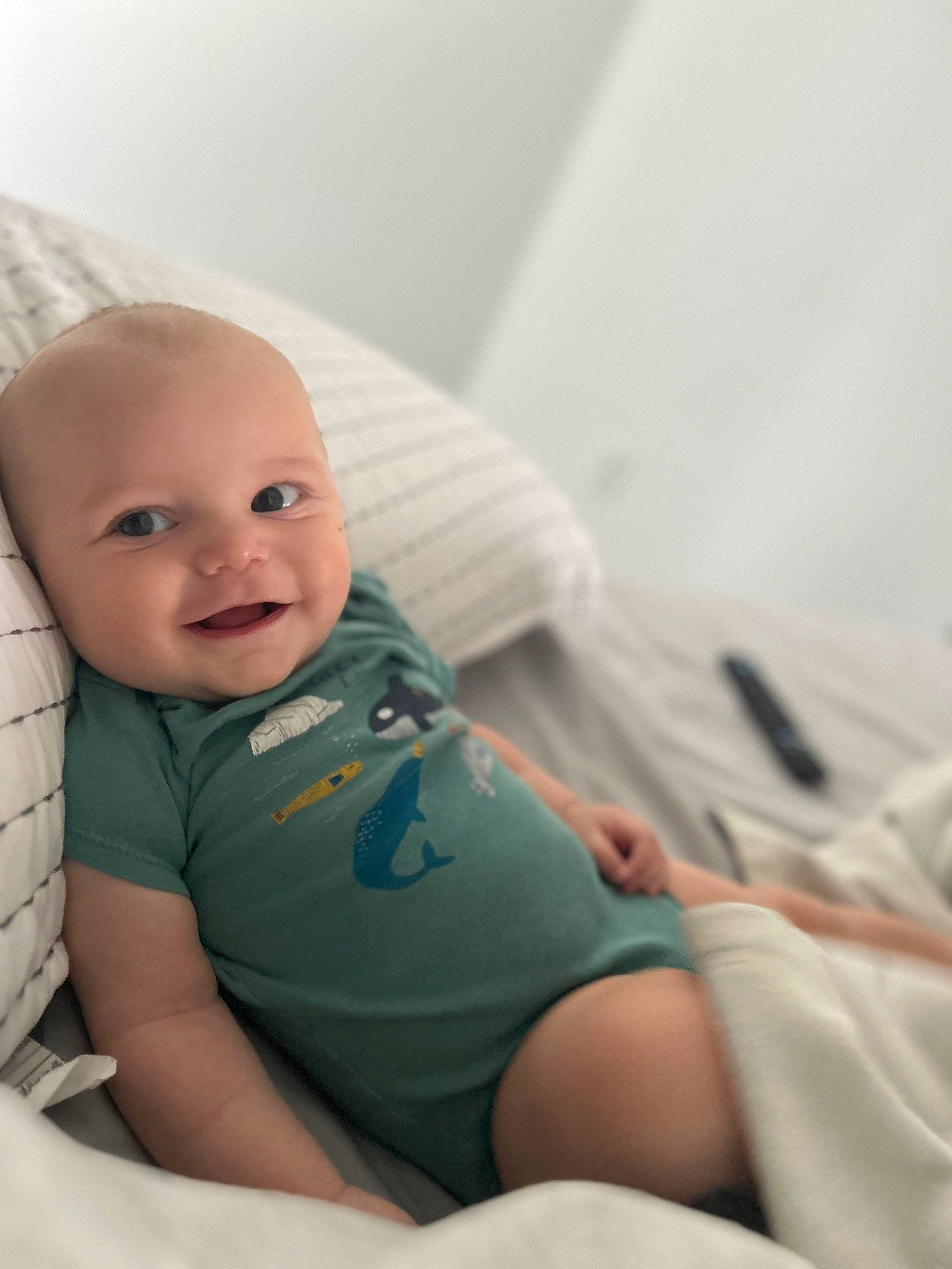 Bennett is registered to the contest to win money with this photo: arm, baby, baby_sleeping, baby_toddler_clothing, child, comfort, elbow, face, happy, head, human_body, human_leg, knee, leg, linens, person, sitting, skin, smile, t_shirt
