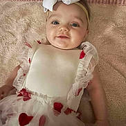 Willow is registered to the contest to win money with this photo: baby, infant, smiling, headband, bow, dress, heart_pattern, tulle, blanket, portrait, eyes, cheeks, lying_down, cute, adorable, arm, fabric, soft_texture, rug, towel