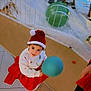 balloon, celebration, child, christmas, curly_hair, decorations, festive, festivity, floor_tiles, holiday, indoor, joyful, person, red_skirt, reindeer, santa_hat, seasonal, smiling, white_sweater, winter