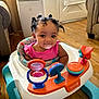 baby, child, infant, walker, toy, pink_clothing, smiling, indoor, living_room, wooden_floor, hair, curly_hair, seat, play, colorful, furniture, cute, young_child, person, happy