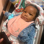 Akira is registered to the contest to win money with this photo: baby, baby_bottle, baby_changing_station, baby_toys, clothing, cozy, cute, denim_jacket, disinfectant, face, floral_blanket, hand, indoor, infant, person, phone, pink_bib, portrait, smiling, soft_lighting