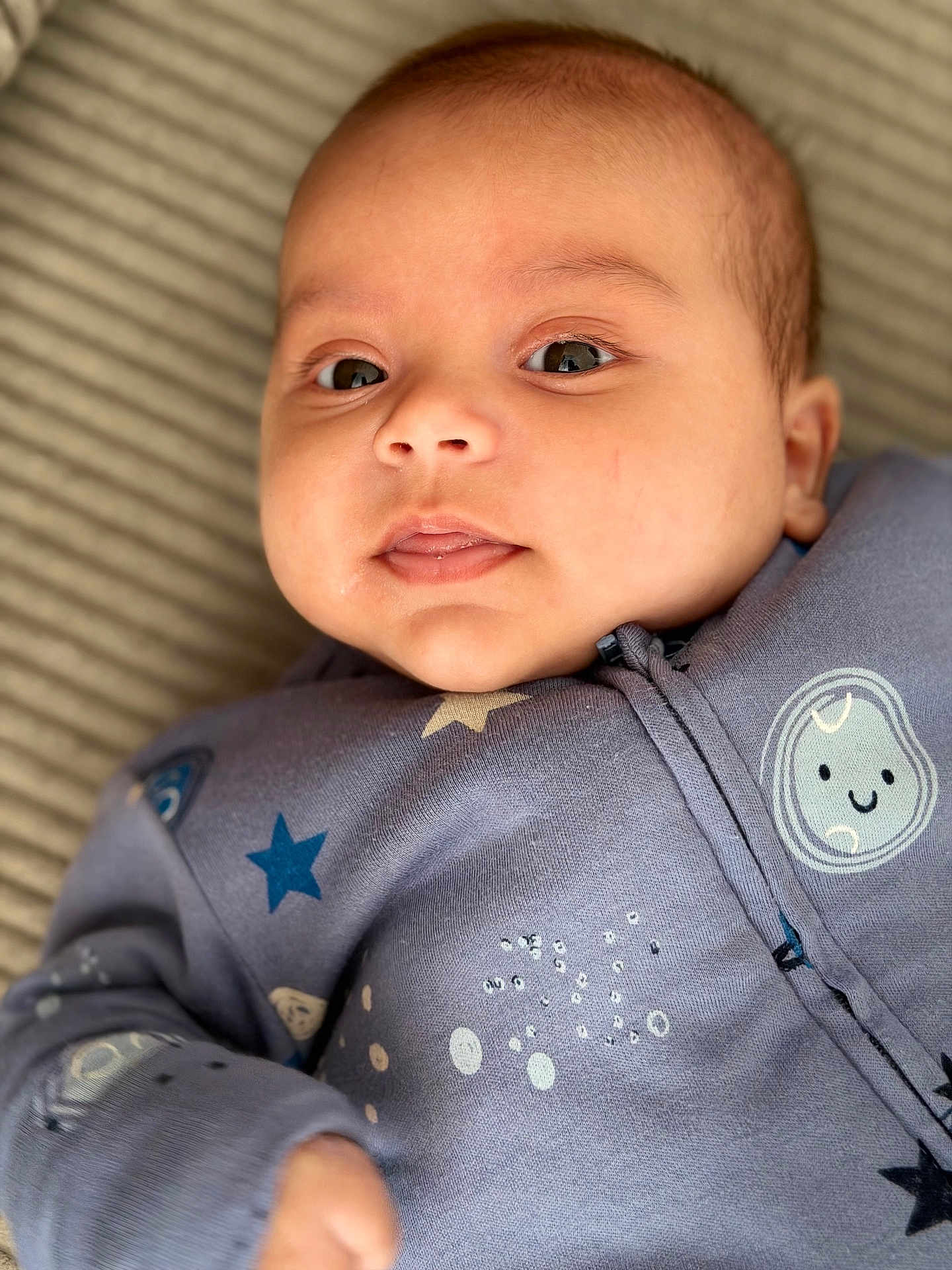 Amir participe au concours pour gagner de l'argent avec cette photo : baby, infant, face, close_up, blue_clothing, stars, moon, sleepwear, cute, lying_down, child, soft_background, portrait, young_child, cozy, expression, skin, eyes, mouth, hand