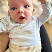 Aaron participe au concours pour gagner de l'argent avec cette photo : baby, infant, face, arm, clothing, white, beige, closeup, expression, person, cute, young, child, skin, eyes, mouth, raised_arm, soft_focus, indoors, portrait
