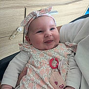 Lexie a rejoint le concours — aidez-le/la à gagner de superbes lots ! baby, child, closeup, clothing, cute, dress, face, hand, happy, headband, holding, indoor, infant, pacifier, pattern, person, pink, skin, smile, white