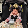 baby, blanket, bottle, car_seat, clothing, cute, duck, head_support, indoor, infant, kitchen, milk, mittens, peaceful, plush_toy, portrait, resting, safety_harness, sleeping, soft_lighting