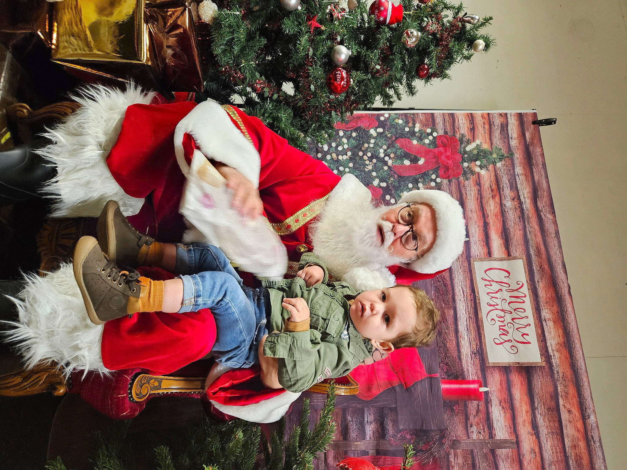 Nathéo participe au concours pour gagner de l'argent avec cette photo : child, christmas, christmas_decoration, christmas_eve, christmas_ornament, christmas_tree, conifer, event, fictional_character, happy, hat, headwear, holiday, holiday_ornament, lap, ornament, person, plant, red, santa_claus