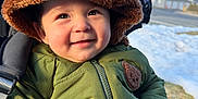 Essex is registered to the contest to win money with this photo: baby, infant, child, stroller, winter_coat, fur_hat, hat, smile, outdoors, snow, jacket, eyes, cheeks, portrait, happy, clothing, cold_weather, stroller_strap, zipper, trees