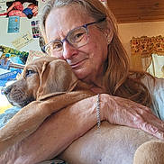Rose is registered to the contest to win money with this photo: bracelet, casual_clothing, curtains, dog, face, fridge, glasses, hand, home, hugging, indoor, long_hair, magnets, pet, photos, puppy, skin, smiling, window, woman