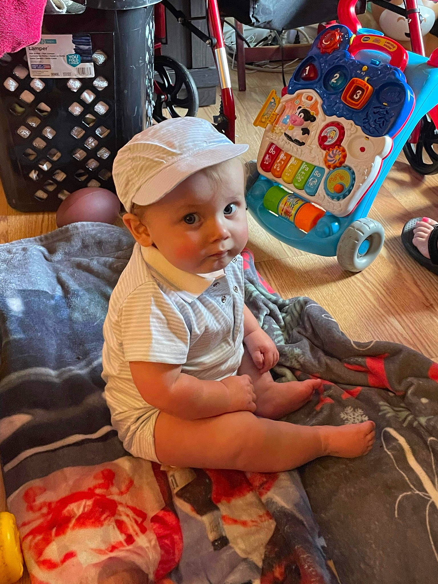 Easton is registered to the contest to win money with this photo: baby, baby_toddler_clothing, baseball_cap, cap, child, cool, event, facial_expression, fun, happy, hat, human_leg, leisure, pattern, person, play, room, sitting, t_shirt, toddler