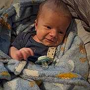 Oliver is registered to the contest to win money with this photo: baby, blanket, blue_blanket, clothing, comfort, cozy, cute, expression, face, hand, head, indoors, infant, newborn, pacifier, person, smiling, soft_texture, warm, wrapped