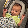 baby, blanket, car_seat, child, clothing, comfort, cushion, cute, face, fan, green_shirt, head_support, indoor, infant, newborn, person, portrait, resting, striped_blanket, toddler