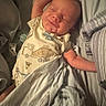 baby, infant, smile, sleeping, bed, blanket, onesie, remote_control, fabric, soft_toy, comfort, peaceful, resting, child, indoor, portrait, sleepwear, cute, newborn, relax