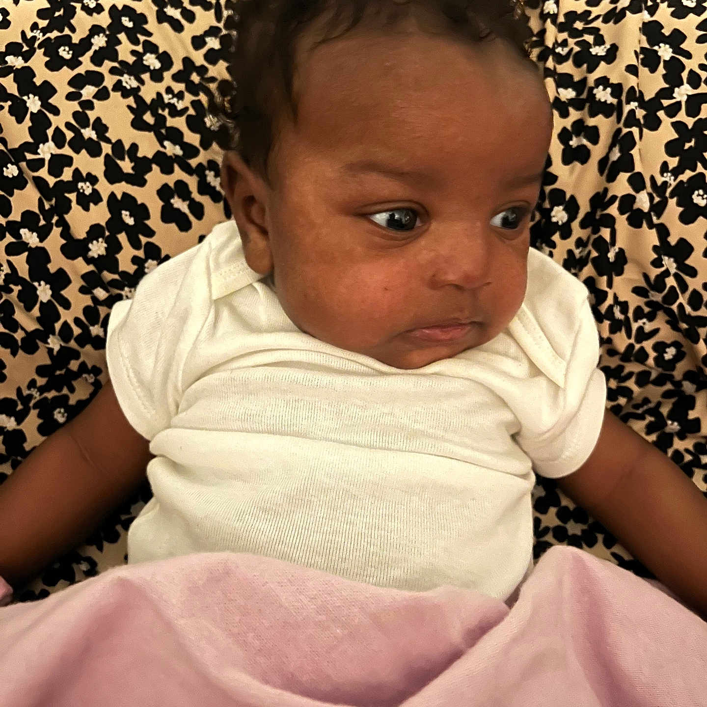 Samanii is registered to the contest to win money with this photo: baby, infant, child, blanket, white_clothing, curly_hair, portrait, indoor, patterned_background, floral_pattern, cute, resting, soft_texture, looking_away, closeup, human, skin, head, face, newborn