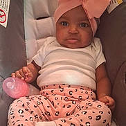 Samanii is registered to the contest to win money with this photo: baby, child, infant, car_seat, pink_bow, headband, pink_bottle, leopard_print, pants, white_shirt, socks, cute, seated, indoors, face, expression, holding, comfort, clothing, infant_toddler