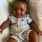 Samanii is registered to the contest to win money with this photo: animal_print, baby, baby_seat, child, clothing, cushion, cute, face, hand, happy, indoor, infant, leg, person, portrait, seat, sitting, skin, smiling, striped_clothing