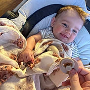 Sterling is registered to the contest to win money with this photo: baby, blanket, pacifier, smile, teddy_bear, cushion, child, infant, hand, striped_shirt, seat, cozy, happy, indoor, person, cute, comfort, light, portrait, young