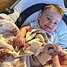 baby, blanket, pacifier, smile, teddy_bear, cushion, child, infant, hand, striped_shirt, seat, cozy, happy, indoor, person, cute, comfort, light, portrait, young