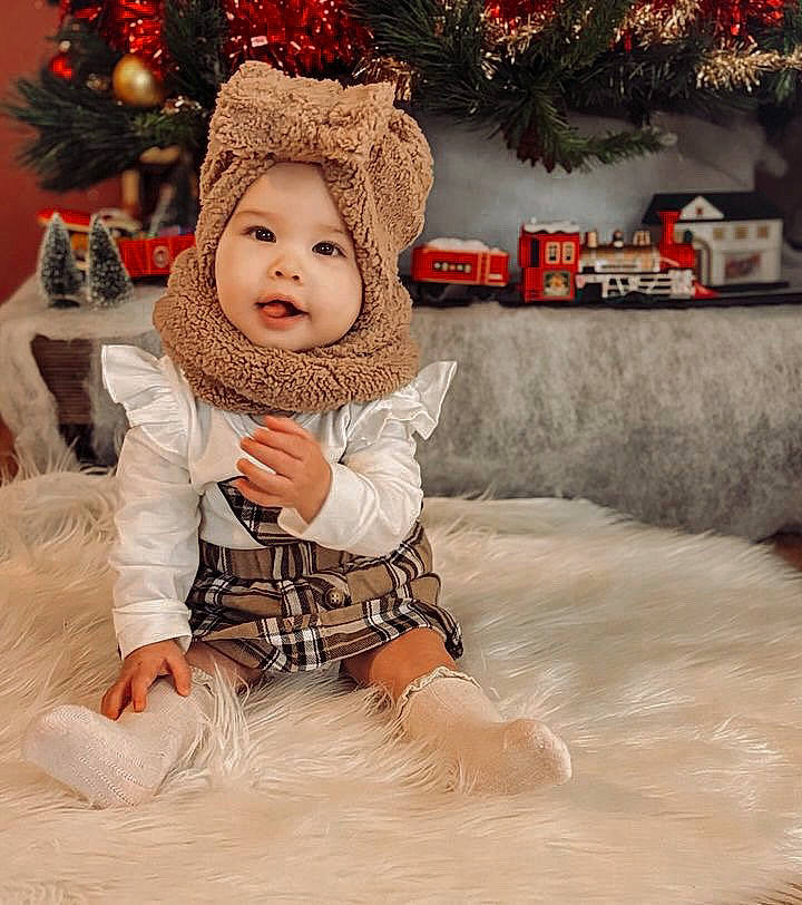 Alba a rejoint le concours — aidez-le/la à gagner de superbes lots ! baby, baby_toddler_clothing, child, christmas, christmas_decoration, christmas_eve, comfort, conifer, event, fur, happy, hat, headwear, holiday, interior_design, ornament, pattern, person, sitting, sleeve