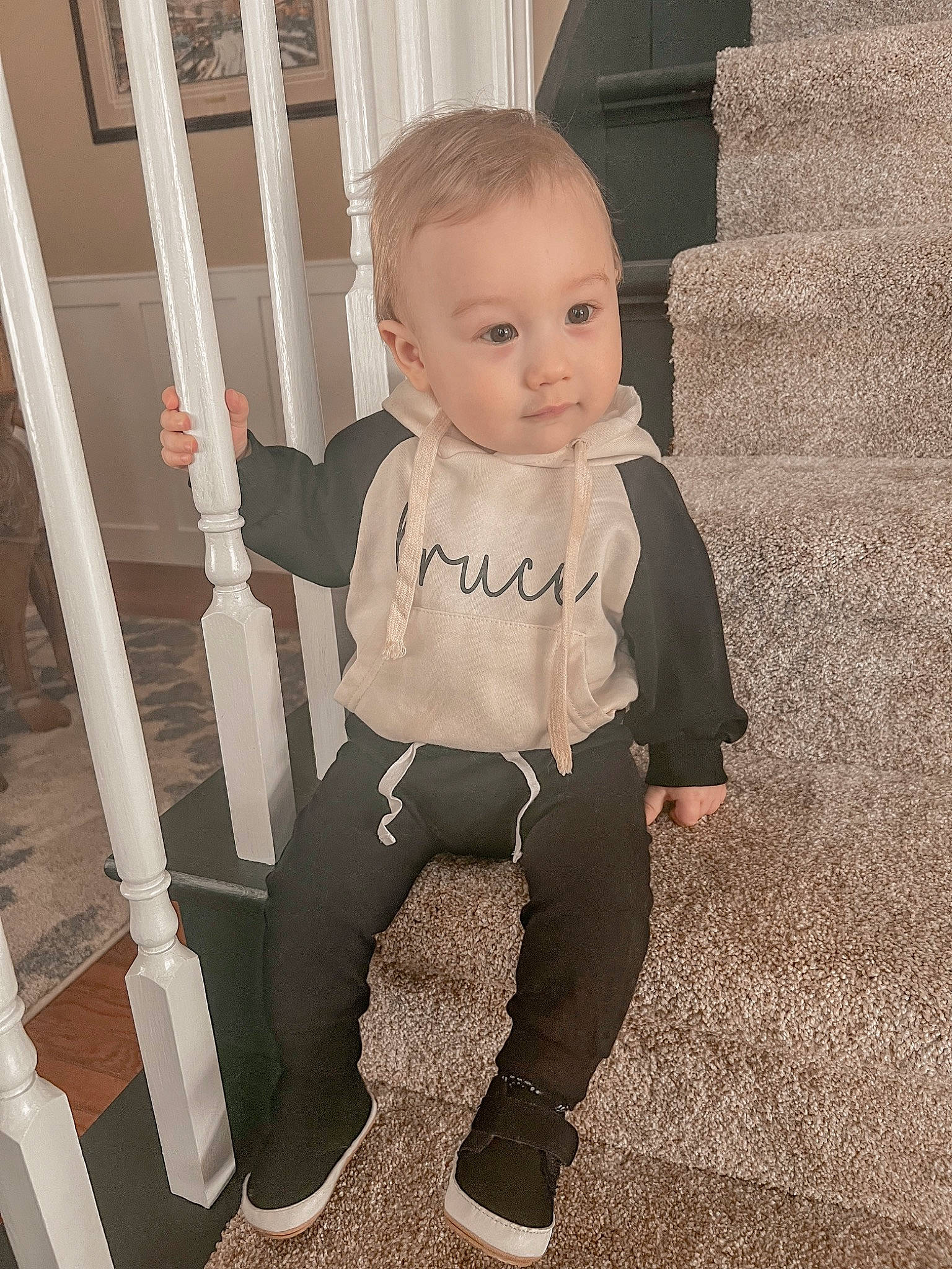 Bruce is registered to the contest to win money with this photo: baby, baby_toddler_clothing, cheek, child, comfort, facial_expression, floor, flooring, hairstyle, human_body, iris, joint, leg, person, shoulder, sitting, sleeve, standing, t_shirt, toddler