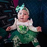 Lainey is registered to the contest to win money with this photo: baby, infant, child, st_patricks_day, green_clothing, headband, tutu, sitting, couch, pillow, patterned, cute, festive, holiday, indoors, person, portrait, happy, clover, celebration