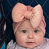 baby, blue_eyes, child, close_up, clothing, cushion, cute, fabric, face, headband, indoor, infant, newborn, pattern, person, pink_bow, portrait, smile, soft_texture, young_child