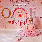 Lainey is registered to the contest to win money with this photo: baby, girl, smiling, pink_dress, tutu, crown, birthday, first_birthday, pacifier, pastel, rainbow, heart, banner, celebration, cute, sitting, indoor, happy, decor, child