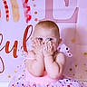 Lainey is registered to the contest to win money with this photo: baby, background, birthday, cake, celebration, child, cute, decoration, dress, face, fun, hands, heart, infant, person, pink, playful, polka_dot, portrait, smile