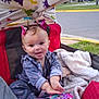baby, child, tongue_out, wagon, blanket, toy_phone, hair_accessory, outdoor, playful, cute, pink, red, smiling, clothing, grass, sidewalk, person, infant, seat, toy