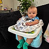 baby, child, infant, blanket, baby_seat, socks, couch, plant, indoor, home, furniture, portrait, person, face, green_socks, patterned_blanket, cozy, casual, seated, cute