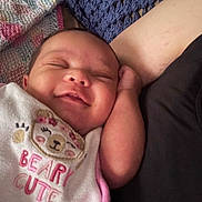 Alaya is registered to the contest to win money with this photo: arm, baby, bib, closeup, clothing, cozy, cute, face, happy, indoors, infant, knitted_blanket, person, pink, portrait, resting, sleeping, smile, soft, white