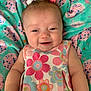 baby, child, smiling, pigtails, bows, dress, floral_pattern, blanket, pastel_colors, happy, cute, infant, lying_down, soft_texture, indoors, closeup, skin, face, person, comfort