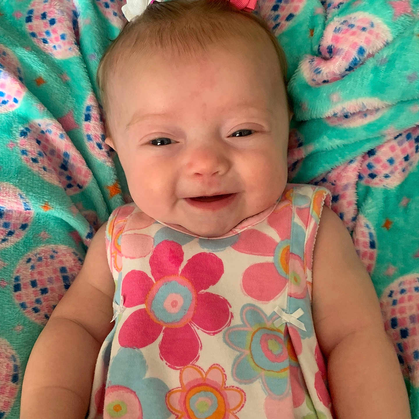 Adilynn joined the competition — help win amazing prizes! baby, blanket, bows, child, closeup, comfort, cute, dress, face, floral_pattern, happy, indoors, infant, lying_down, pastel_colors, person, pigtails, skin, smiling, soft_texture