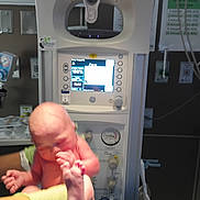 Grayson joined the competition — help win amazing prizes! newborn, baby, infant, medical_equipment, hospital, warmer, monitor, gloves, hands, skin, nurse, delivery_room, vacuum_gauge, tubing, display_screen, healthcare, hospital_room, clinical, blurry, close_up