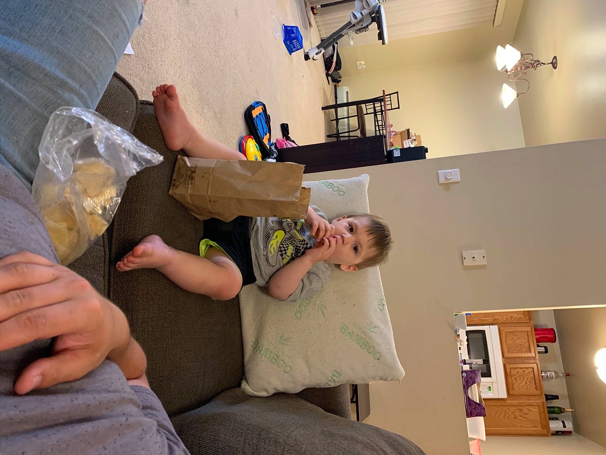 Brenden is registered to the contest to win money with this photo: ceiling, child, comfort, couch, elbow, fun, hand, human_leg, joint, knee, leisure, machine, person, picture_frame, room, shelf, shorts, sitting, t_shirt, thigh