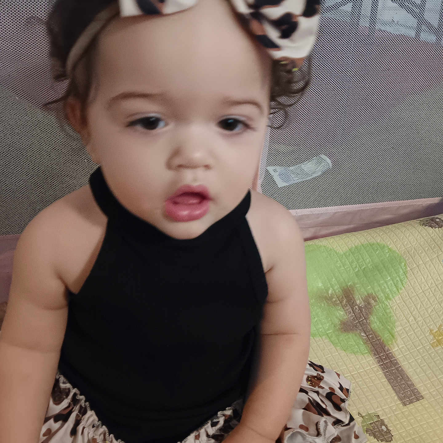 Aryiah joined the competition — help win amazing prizes! baby, black_top, child, clothing, curly_hair, cute, expression, face, hand, headband, indoor, infant, leopard_print, person, play_mat, portrait, sitting, skirt, toddler, young_child