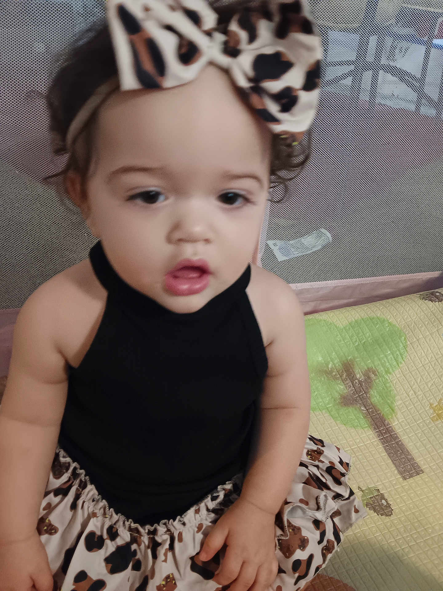 Aryiah joined the competition — help win amazing prizes! toddler, child, baby, headband, curly_hair, black_top, leopard_print, skirt, play_mat, indoor, portrait, person, cute, young_child, sitting, infant, face, hand, clothing, expression