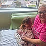 baby, bed, blanket, caring, child, curtain, family, glasses, holding, hospital, indoor, love, newborn, parking_lot, pink_shirt, seated, smile, trees, window, woman