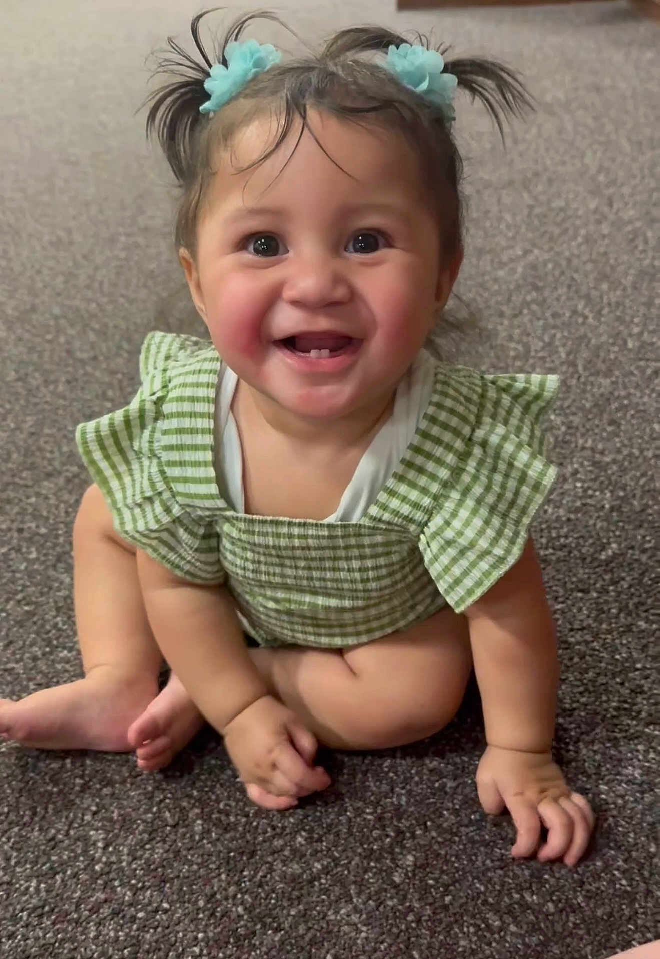 Lesieli is registered to the contest to win money with this photo: baby, child, smiling, pigtails, blue_flower_clips, green_outfit, checkered, carpet, cute, happy, sitting, hands, feet, indoors, portrait, infant, adorable, face, eyes, tooth