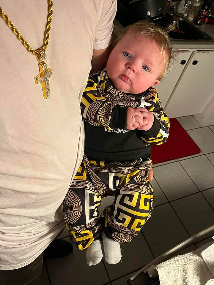 Kendrick participe au concours pour gagner de l'argent avec cette photo : abdomen, baby, baby_toddler_clothing, black, chest, child, fashion_design, gesture, happy, human_leg, jewellery, knee, leg, pattern, person, personal_protective_equipment, sleeve, t_shirt, thigh, toddler