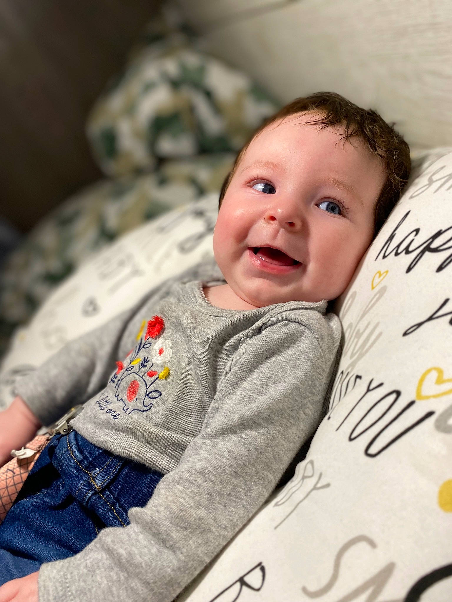 Magnolia is registered to the contest to win money with this photo: baby, baby_toddler_clothing, cheek, child, comfort, face, grey, happy, iris, linens, pattern, person, product, room, sitting, skin, sleeve, smile, t_shirt, textile