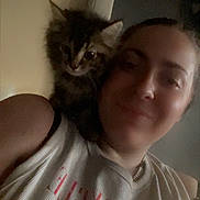 Simba is registered to the contest to win money with this photo: person, cat, kitten, shoulder, indoor, portrait, smile, furry, closeup, pet, animal, casual, tank_top, chain_necklace, hair, face, feline, companion, cozy, soft_lighting