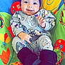 Cali joined the competition — help win amazing prizes! baby, child, smile, headband, purple_flower, grey_outfit, cartoon_prints, boots, colorful_chair, play_chair, indoor, happy, person, infant, cute, seated, clothing, patterned, bright_colors, portrait