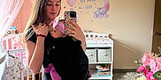 Cali is registered to the contest to win money with this photo: baby, woman, nursery, mirror_selfie, baby_carrier, pink_canopy, wall_decor, elephant_decal, crescent_moon, stars, baby_clothes, changing_table, flower_arrangement, water_bottle, mirror, carpet, door, wooden_furniture, headband, smile