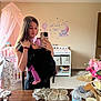 baby, woman, nursery, mirror_selfie, baby_carrier, pink_canopy, wall_decor, elephant_decal, crescent_moon, stars, baby_clothes, changing_table, flower_arrangement, water_bottle, mirror, carpet, door, wooden_furniture, headband, smile