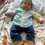 Jai Mari joined the competition — help win amazing prizes! baby, child, infant, striped_shirt, navy_pants, tan_shoes, curly_hair, bed, blanket, holiday_theme, reindeer_pattern, pillow, lying_down, cute, smiling, indoors, cozy, colorful, person, portrait