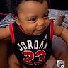 Prince joined the competition — help win amazing prizes! baby, child, smiling, curly_hair, jordan_jersey, black_clothing, red_clothing, sitting, indoor, person, cute, portrait, happy, infant, legs, hands, face, room, furniture, cozy